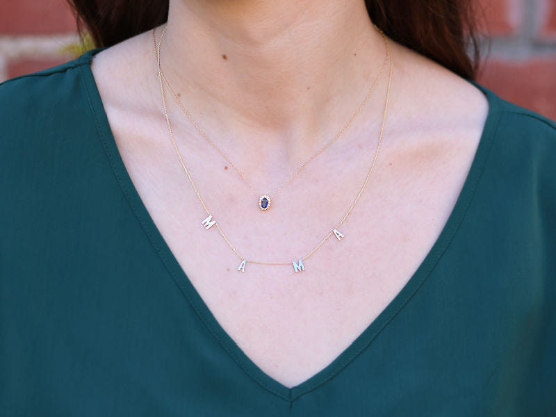 14k yellow "MAMA" and sapphire halo necklace on a neck