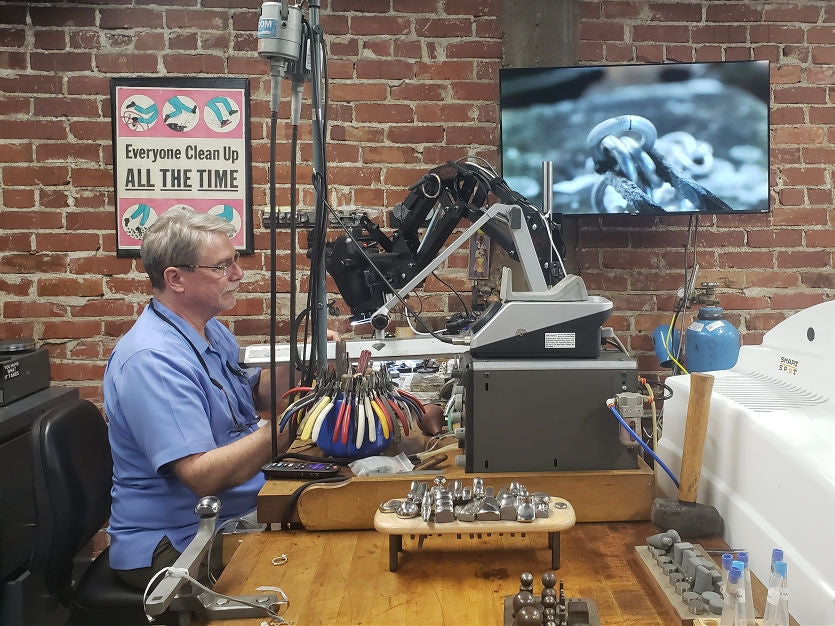 George Fox at his workbench soldering a sterling silver link. Find the hidden objects!