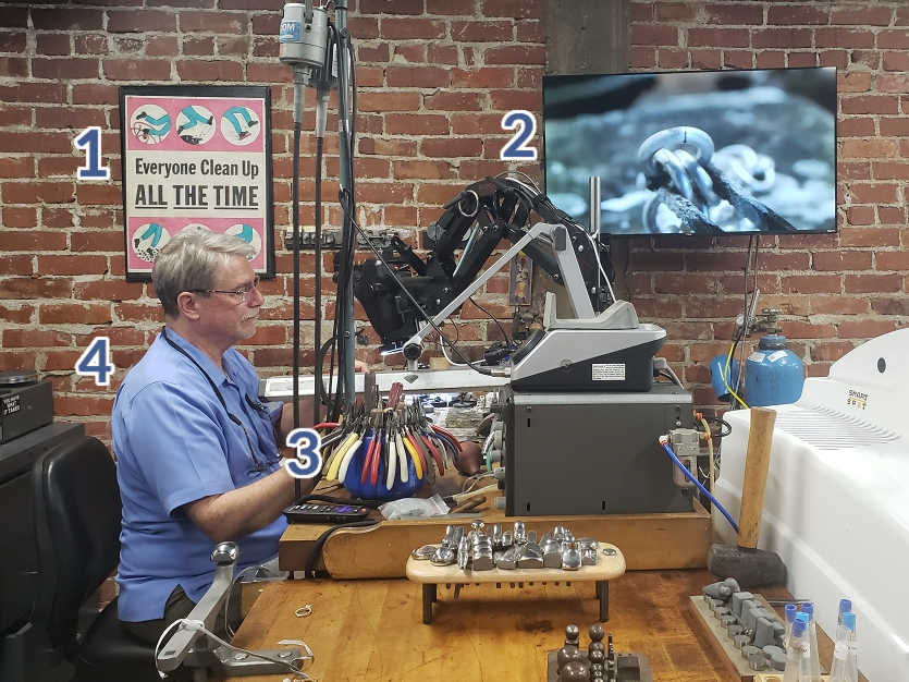 George Fox at his workbench soldering a sterling silver link. The hidden objects numbered