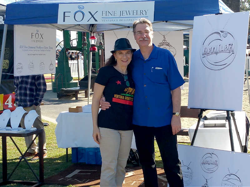 Debbie and George Fox standing under a 'Fox Fine Jewelry' tent at an outdoor event.