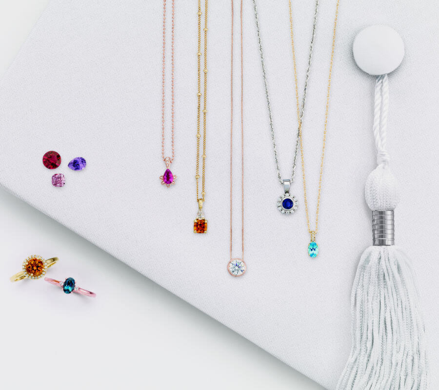 Four different classic necklaces and two rings on a graduation cap