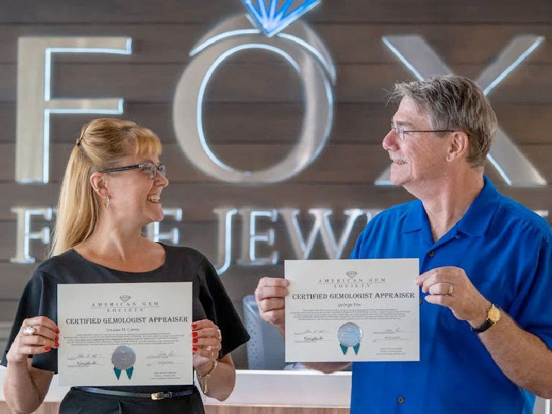 Louisa May Carey and George Fox holding their AGS Certified Gemologist Appraiser certificates