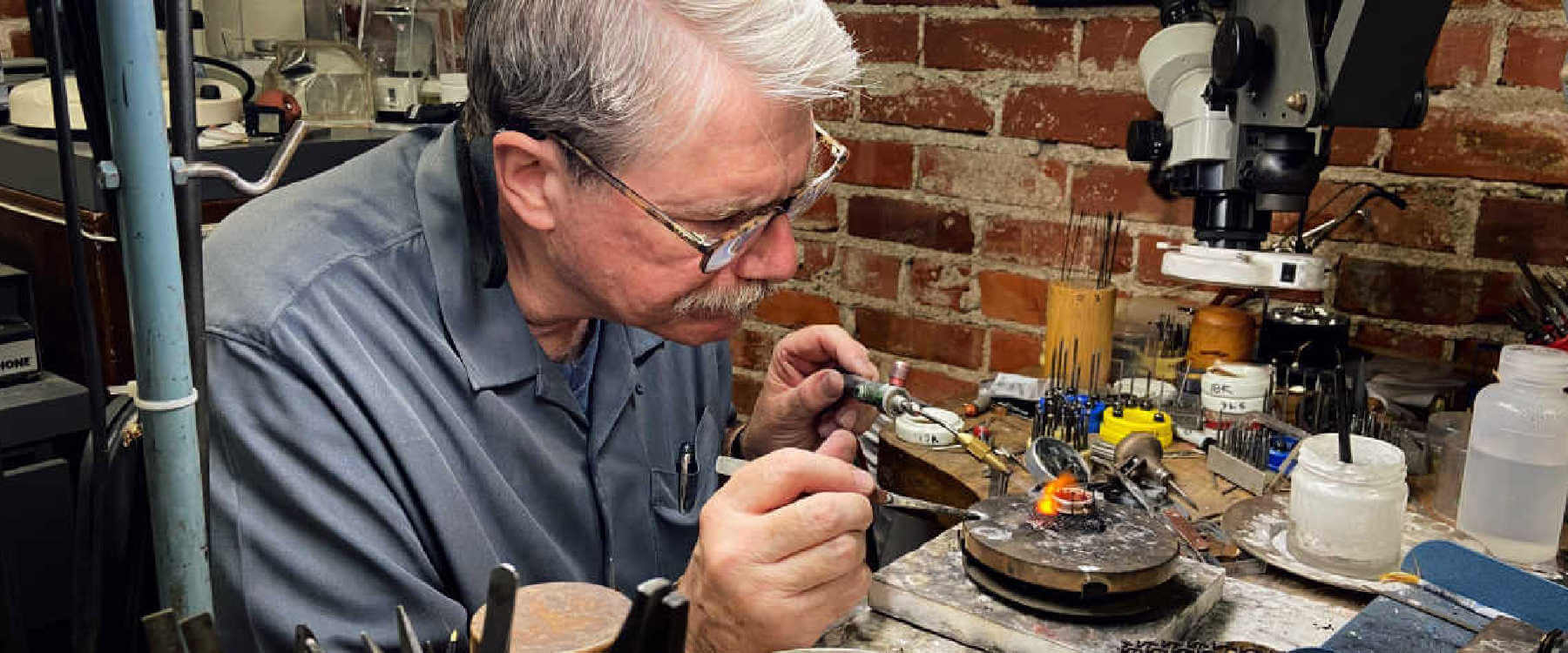 George Fox soldering a ring at his work bench