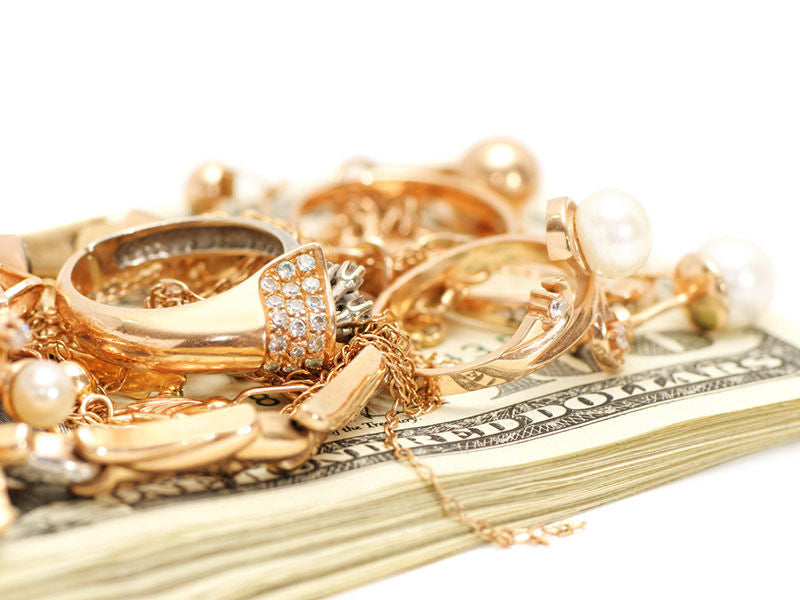 Yellow gold jewelry on a stack of money