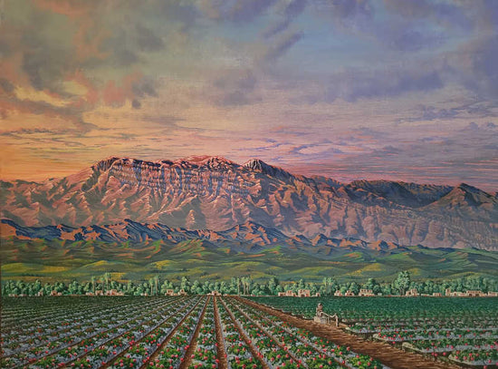 A landscape painting depicting a vast agricultural field with neat rows of crops leading toward a large mountain range under a dramatic, cloudy sky at sunset. Topa Topa by Zrondeb
