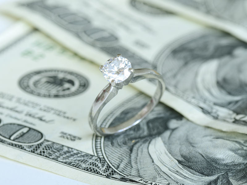 Diamond solitaire engagement ring on money