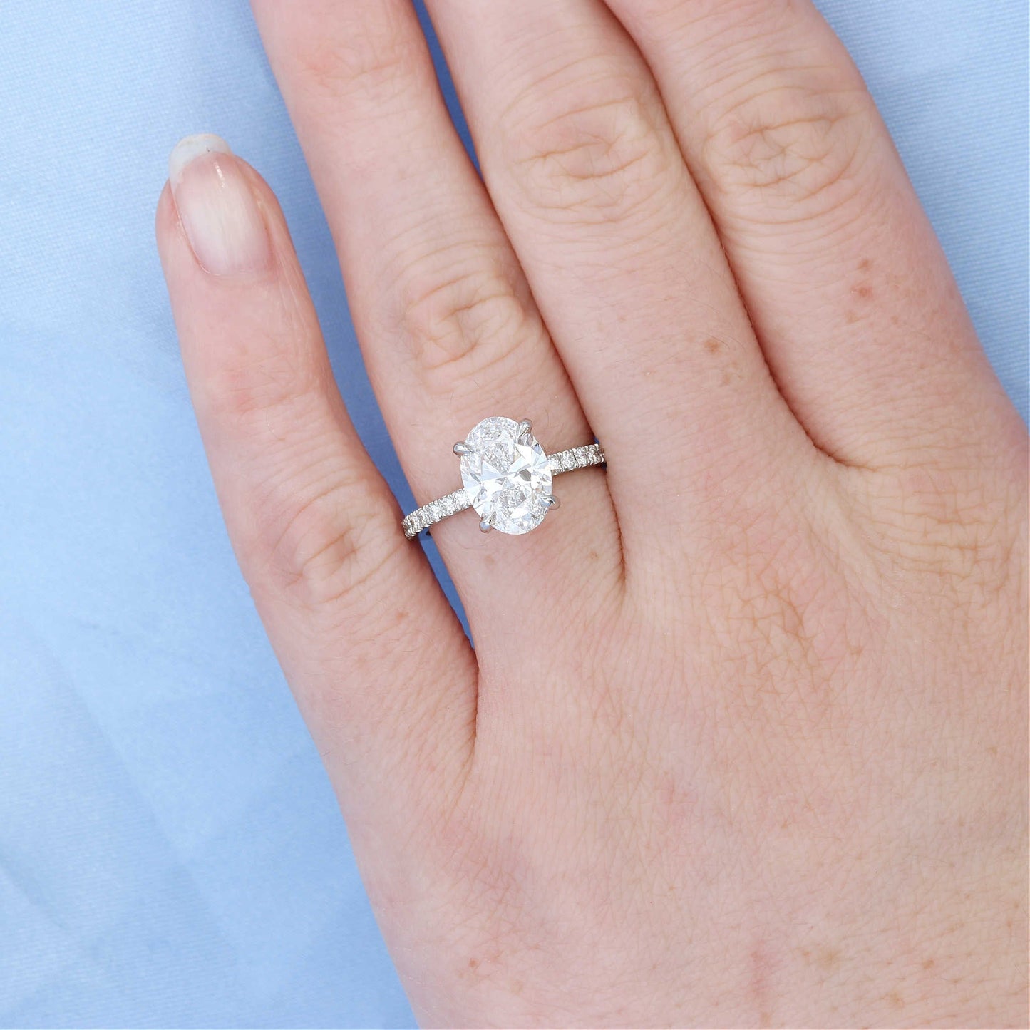 Platinum Hidden Halo Oval Diamond Engagement Ring on a Finger
