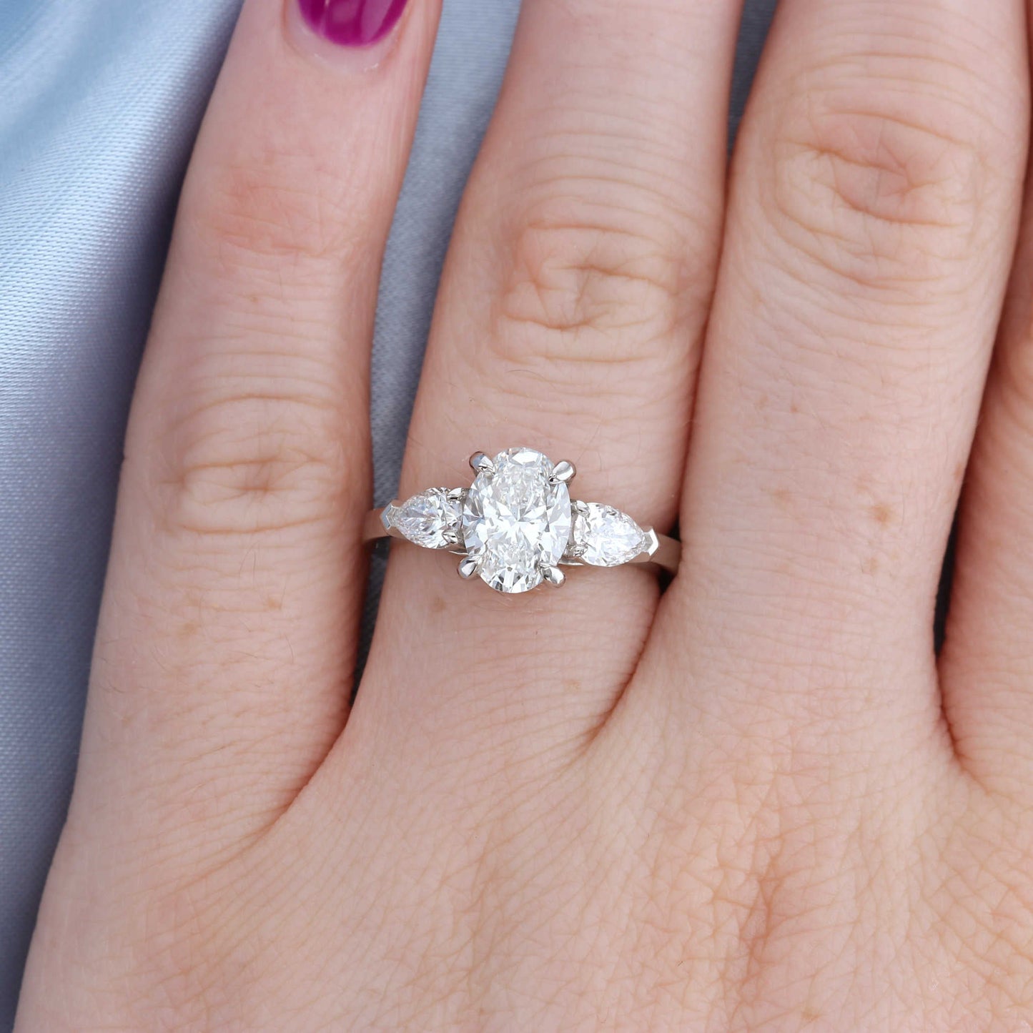Platinum Oval Three Stone Diamond Engagement Ring on a Finger