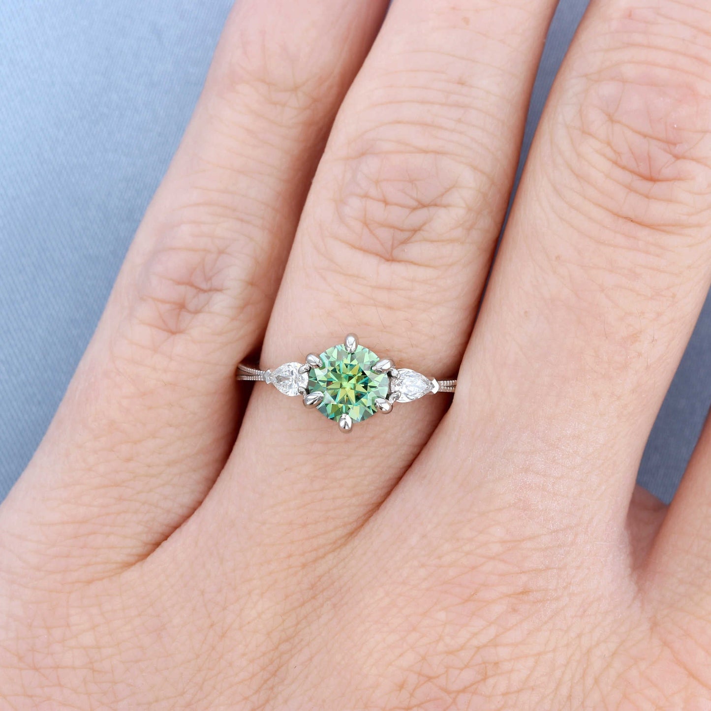 Green Moissanite Three Stone Engagement Ring on a Finger